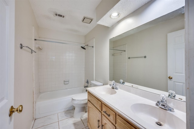 full bathroom with tiled shower / bath combo, tile patterned flooring, a textured ceiling, toilet, and vanity