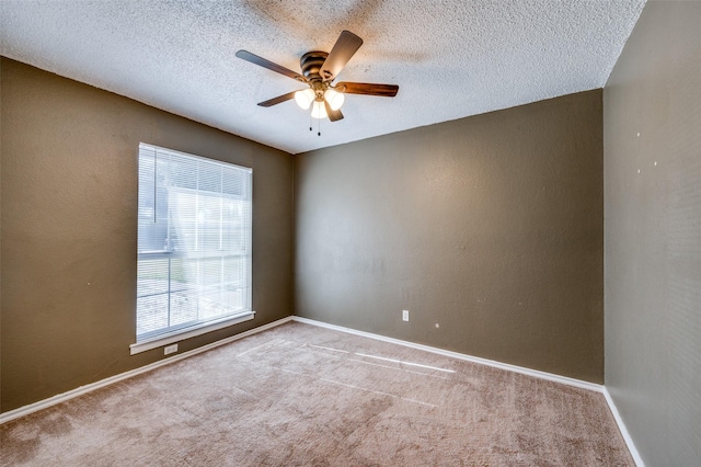 empty room featuring ceiling fan, light carpet, and a textured ceiling