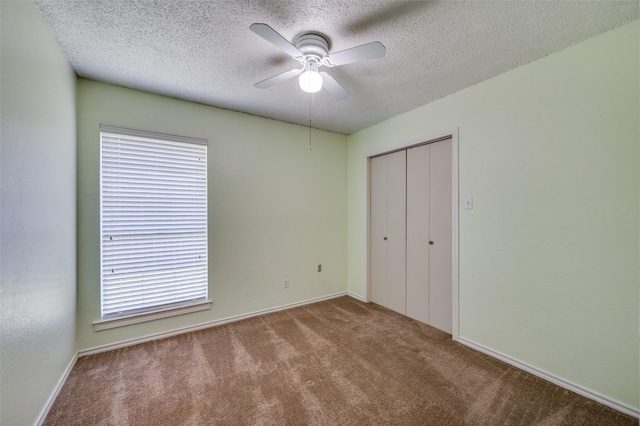 unfurnished bedroom with ceiling fan, multiple windows, a textured ceiling, light carpet, and a closet