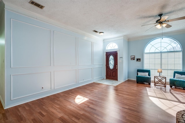 entryway featuring ceiling fan, ornamental molding, a textured ceiling, and light hardwood / wood-style flooring