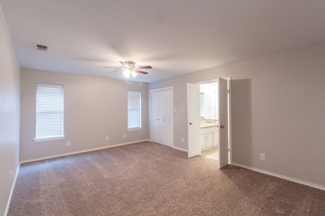 interior space with carpet flooring, ensuite bath, and ceiling fan