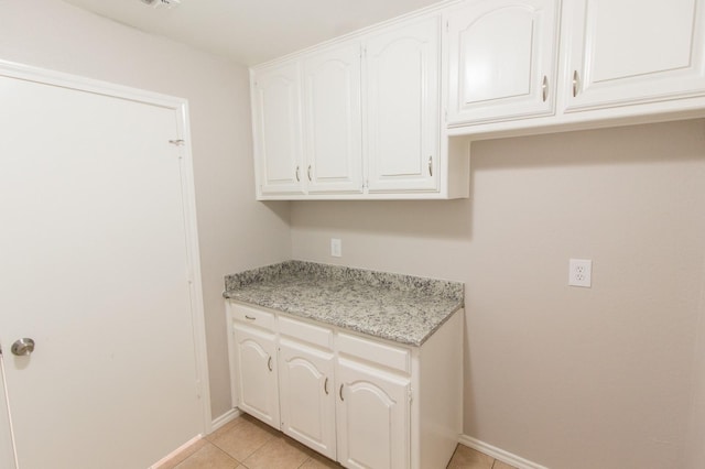 kitchen featuring light stone counters, white cabinetry, and light tile patterned floors