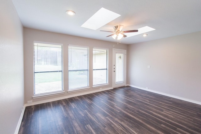 unfurnished room with ceiling fan, dark hardwood / wood-style flooring, and a skylight