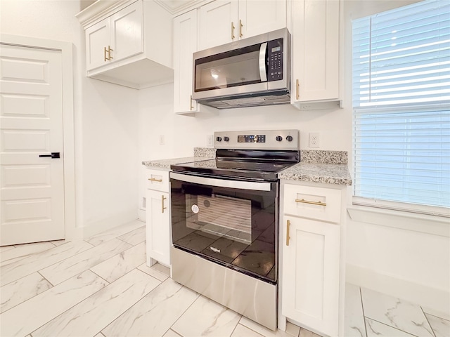 kitchen with white cabinetry, light stone countertops, and appliances with stainless steel finishes