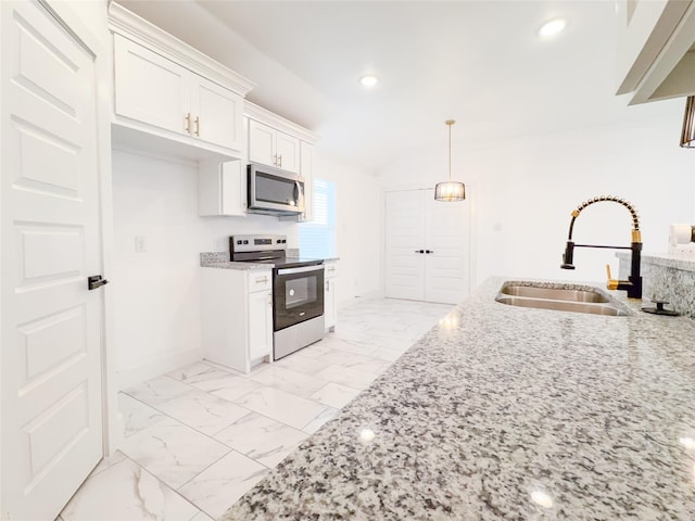 kitchen featuring light stone countertops, appliances with stainless steel finishes, vaulted ceiling, sink, and white cabinetry