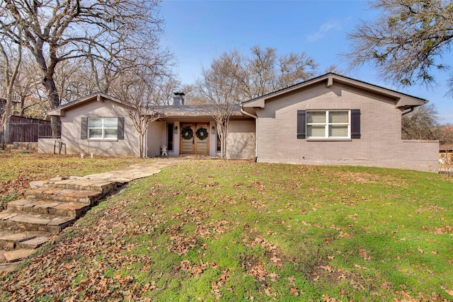 single story home with brick siding, a chimney, a front yard, and fence