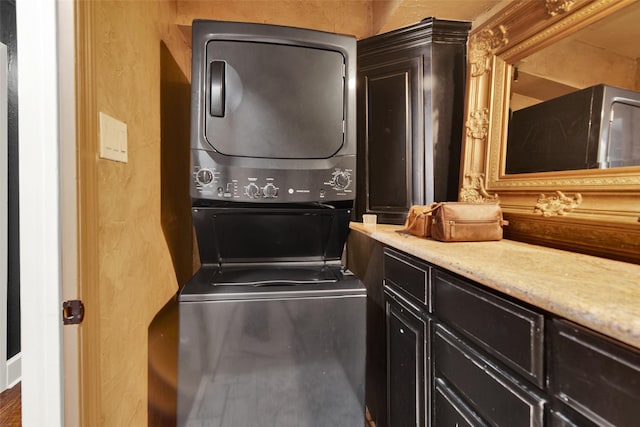 laundry area with stacked washer / dryer and cabinets