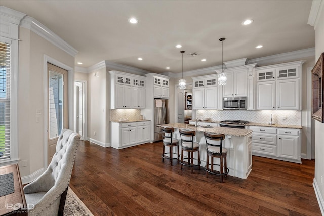 kitchen with white cabinetry, appliances with stainless steel finishes, an island with sink, and hanging light fixtures