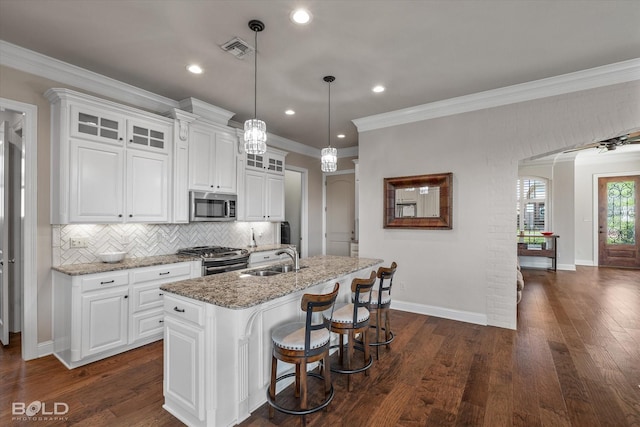 kitchen featuring stainless steel appliances, white cabinetry, and a center island with sink