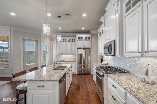 kitchen featuring appliances with stainless steel finishes, a kitchen breakfast bar, an island with sink, pendant lighting, and white cabinets