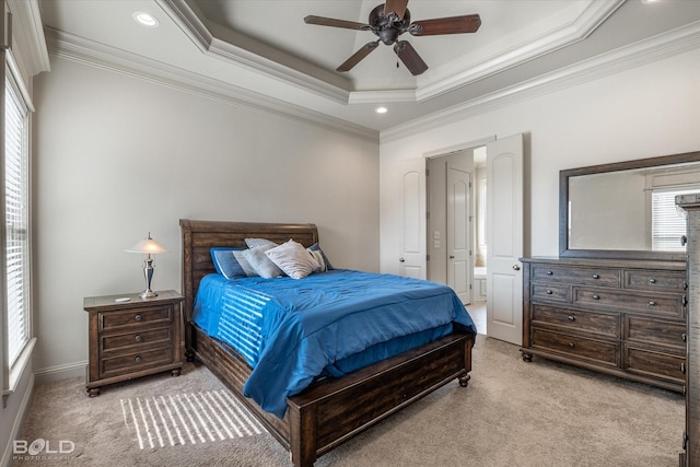 bedroom with crown molding, light colored carpet, ensuite bathroom, and a tray ceiling