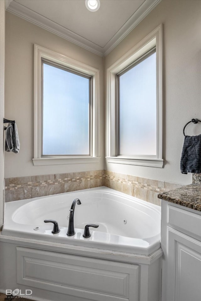 bathroom with ornamental molding, vanity, and a tub to relax in