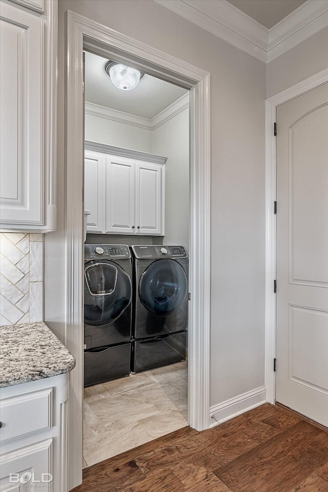 clothes washing area featuring separate washer and dryer, crown molding, wood-type flooring, and cabinets