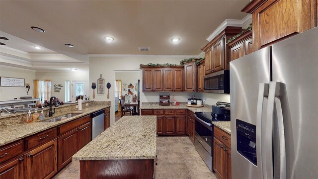 kitchen with a center island, sink, ornamental molding, light stone counters, and stainless steel appliances