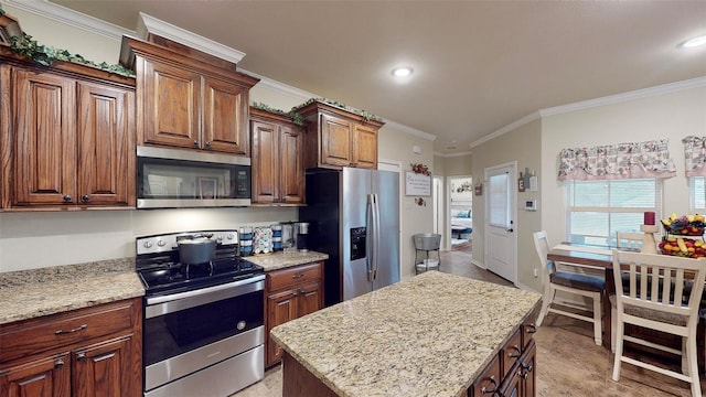 kitchen featuring light stone countertops, a center island, stainless steel appliances, and ornamental molding