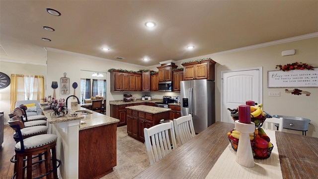 kitchen with a breakfast bar, stainless steel appliances, crown molding, sink, and a center island with sink