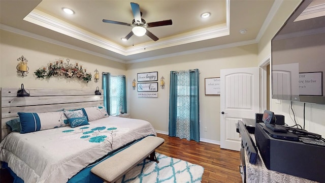 bedroom featuring ceiling fan, dark hardwood / wood-style flooring, crown molding, and a tray ceiling