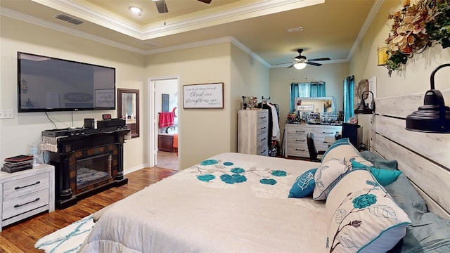 bedroom with ceiling fan, ornamental molding, and dark wood-type flooring