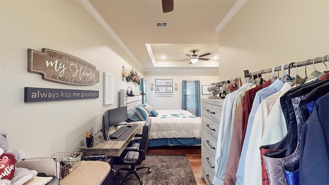 bedroom featuring a raised ceiling, crown molding, ceiling fan, and dark wood-type flooring