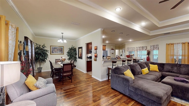 living room with crown molding, dark hardwood / wood-style flooring, and ceiling fan with notable chandelier