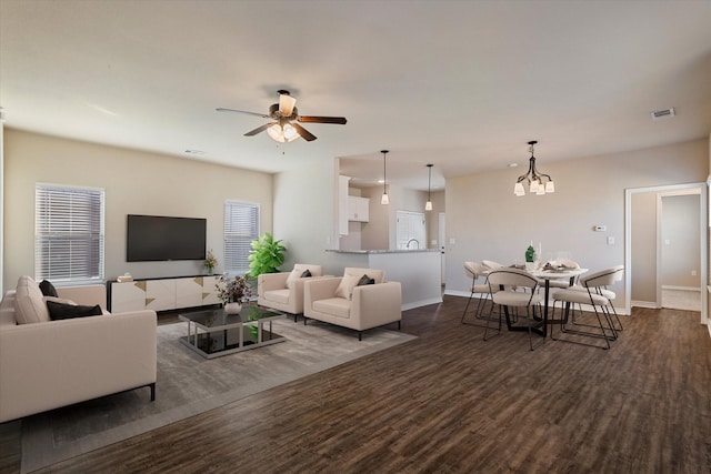 living room featuring ceiling fan with notable chandelier and dark wood-type flooring