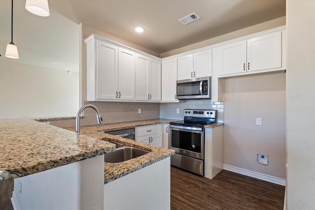 kitchen featuring light stone countertops, hanging light fixtures, stainless steel appliances, kitchen peninsula, and white cabinets