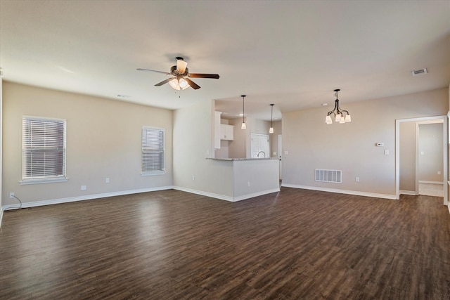 unfurnished living room featuring dark wood-type flooring and ceiling fan with notable chandelier