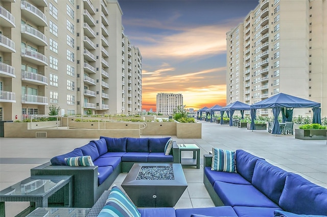 patio terrace at dusk featuring a gazebo and an outdoor living space with a fire pit