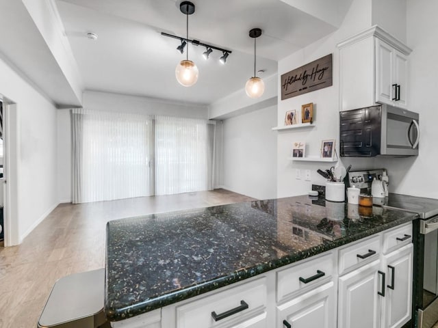 kitchen with rail lighting, stainless steel appliances, light hardwood / wood-style flooring, dark stone counters, and white cabinets