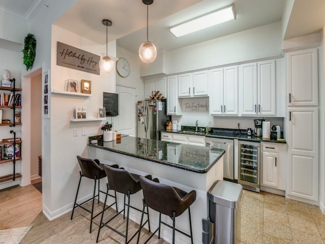 kitchen featuring white cabinets, stainless steel appliances, kitchen peninsula, and beverage cooler