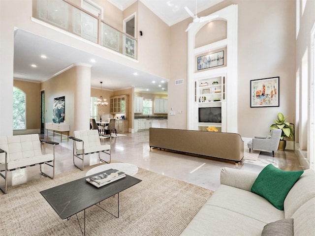 living room featuring visible vents, a chandelier, built in features, ornamental molding, and a high ceiling