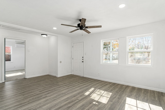 unfurnished room with ceiling fan, an AC wall unit, and dark hardwood / wood-style flooring