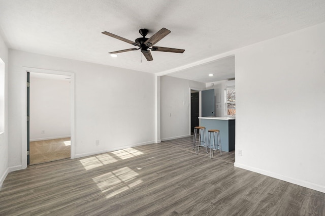 unfurnished living room with ceiling fan, dark hardwood / wood-style flooring, and a textured ceiling