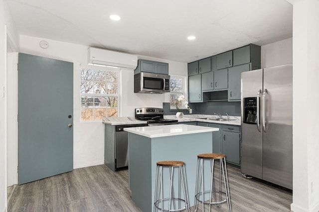 kitchen featuring sink, a breakfast bar area, a wall mounted AC, a center island, and stainless steel appliances