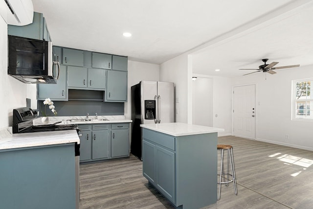 kitchen with sink, wood-type flooring, stainless steel appliances, and a center island