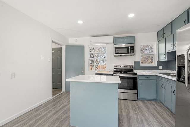 kitchen with stainless steel appliances, an AC wall unit, a healthy amount of sunlight, and light hardwood / wood-style flooring