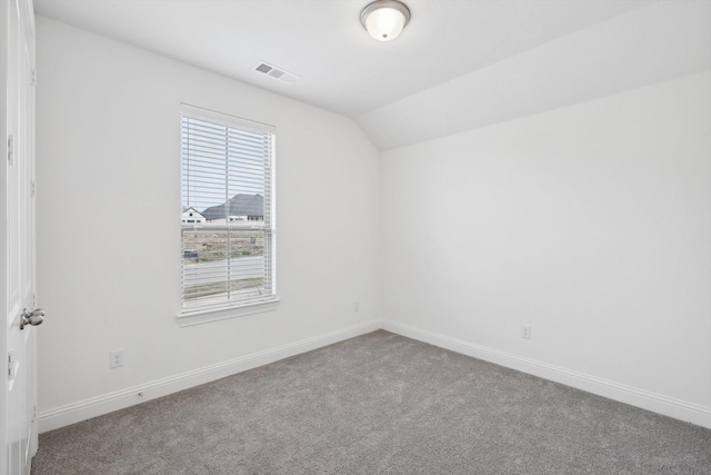 carpeted spare room with vaulted ceiling