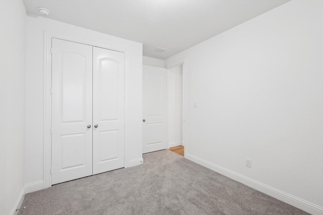 unfurnished bedroom with light colored carpet and a closet