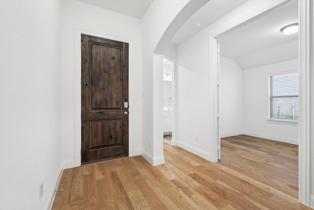 foyer entrance with vaulted ceiling and light wood-type flooring