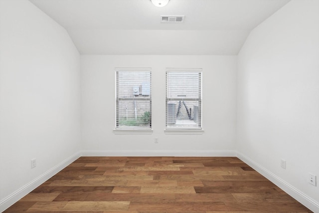 spare room with dark wood-type flooring and lofted ceiling