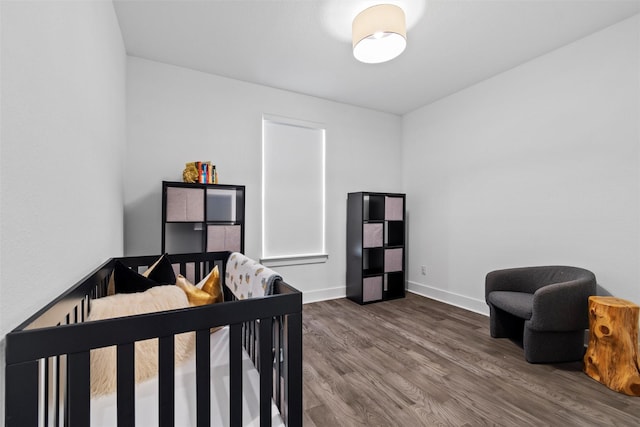 bedroom featuring a crib and hardwood / wood-style flooring