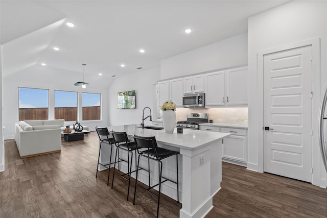 kitchen featuring stainless steel appliances, sink, white cabinetry, lofted ceiling, and a kitchen island with sink