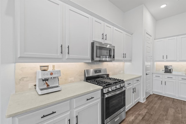 kitchen with white cabinetry, stainless steel appliances, dark wood-type flooring, and light stone counters