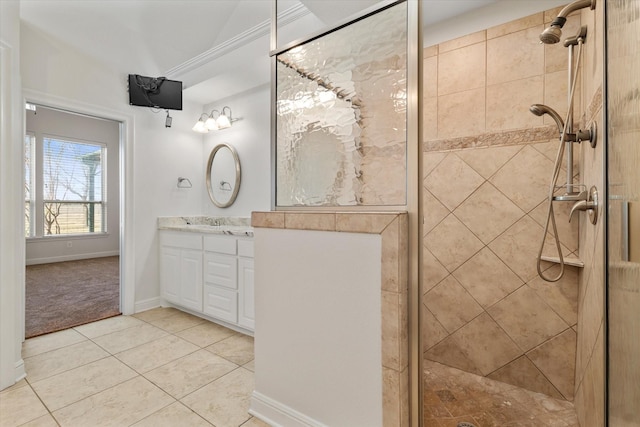 full bath with tile patterned flooring, a tile shower, vanity, and baseboards