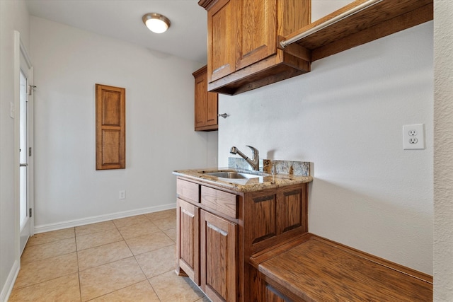 kitchen with sink, light tile patterned flooring, and light stone countertops