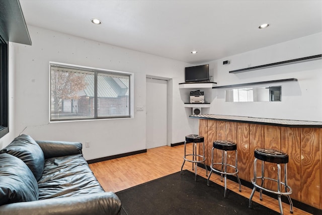 living room with bar and light hardwood / wood-style flooring