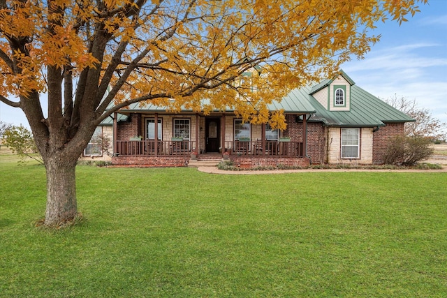 view of front facade featuring metal roof, covered porch, a standing seam roof, a front lawn, and brick siding