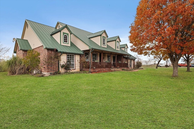 view of front of property featuring metal roof, a standing seam roof, a front yard, a porch, and brick siding