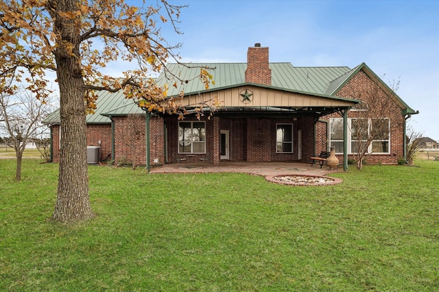 back of property with a patio, brick siding, a standing seam roof, and a chimney