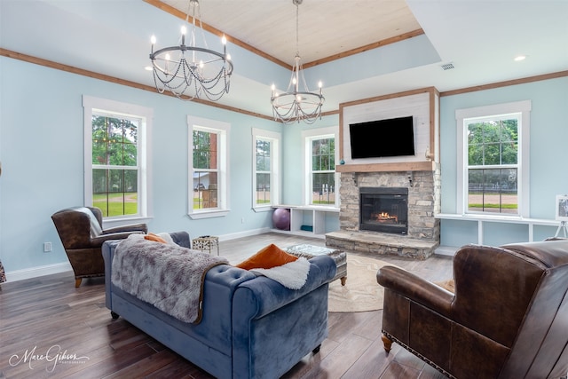 living room with dark hardwood / wood-style floors, a tray ceiling, a chandelier, and a stone fireplace